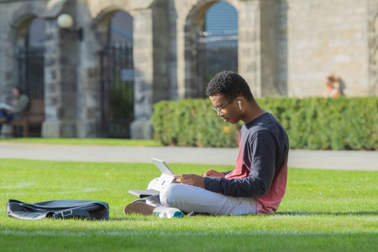 A student sitting outside with a laptop